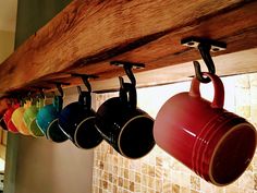 coffee mugs are hanging from a wooden rack with the words home and garden essentials on it