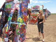 a woman standing in front of a large elephant sculpture with graffiti on it's side