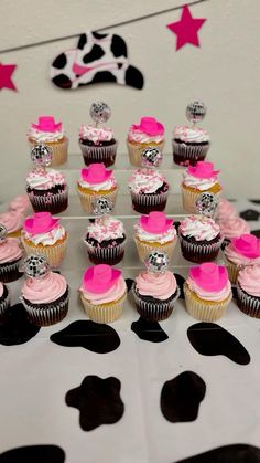 a table topped with lots of cupcakes covered in frosting and pink icing