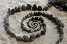 a spiral made out of rocks in the sand