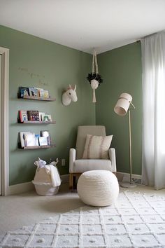 a chair and ottoman in a room with green walls, white carpeting and hanging decorations