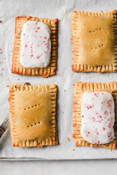 four crackers with white icing and pepperoni sprinkled on them