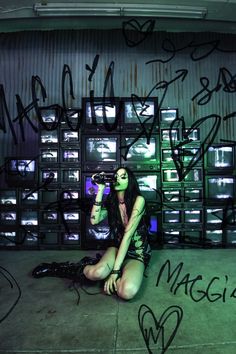 a woman sitting on the ground with graffiti all over her