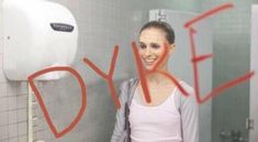 a woman standing in front of a urinal with the word joy painted on it