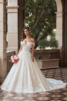 a woman in a white wedding dress standing on a tile floor next to an archway