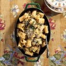 a pan filled with pasta and sauce on top of a table next to two bowls