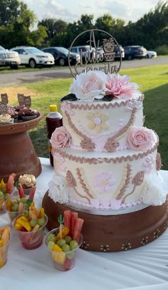 a three tiered cake sitting on top of a table next to cupcakes