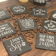 slate coasters with coffee sayings on them and coffee beans scattered around the coaster