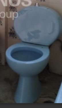 a blue toilet sitting in a bathroom next to a wall with writing on the walls