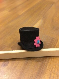 a black top hat with a pink flower on it sitting next to a wooden frame