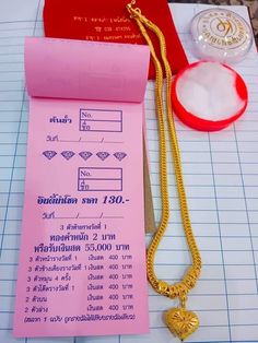 a pink paper with a gold necklace on top of it next to a pair of scissors