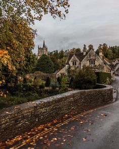 an old stone bridge over a small river in the middle of a village surrounded by trees