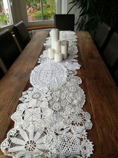 a long table with white doily and candles on it