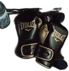 two black boxing gloves sitting next to a water bottle