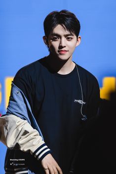 a young man with headphones on standing in front of a blue wall