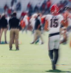 a blurry photo of a football player holding his hand out to the sideline