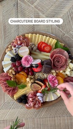 a platter filled with different types of cheese and meats on top of a wooden table