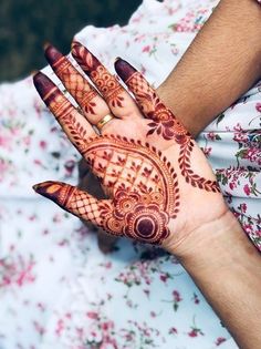 a woman's hands with hennap on her hand and flowers all around