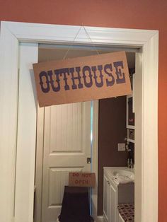 an outhouse sign hanging from a door