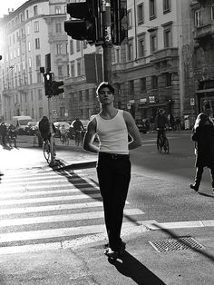 black and white photograph of a man walking across the street in front of traffic lights