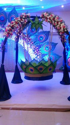 an elaborately decorated swing with flowers and peacock feathers