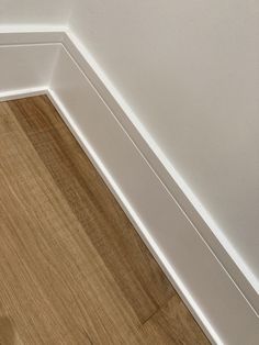 the corner of a room with wood floors and white walls