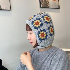 a woman wearing a crocheted hat with flowers on it