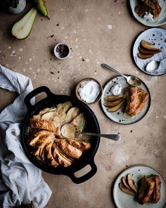 a pan filled with food on top of a table next to plates and utensils