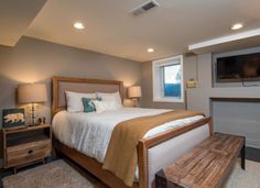 a bedroom with a bed, dresser and television on the wall next to a fireplace