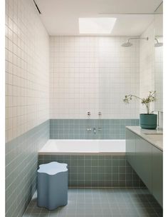 a bath tub sitting next to a white sink under a window in a tiled bathroom