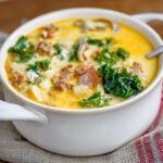 a white bowl filled with soup on top of a table next to a napkin and spoon