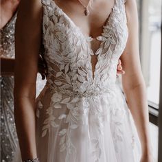 a woman in a wedding dress standing next to a window