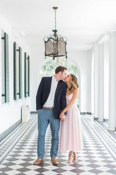 an engaged couple kissing in the hallway at their wedding reception, with chandelier hanging from the ceiling