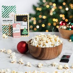 a wooden bowl filled with popcorn next to a christmas tree and other holiday decorations on a table