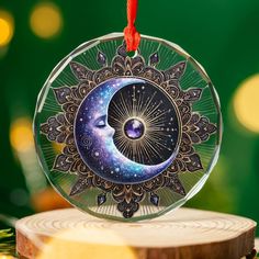 a glass ornament with an image of the moon and stars on it hanging from a red string