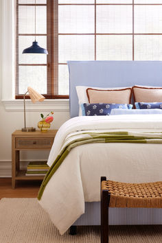 a bed with blue and white bedspread in a bedroom next to a window