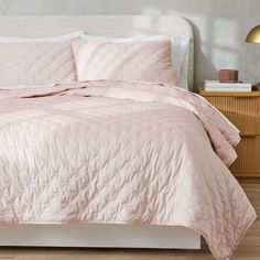 a bed with a pink comforter and pillows