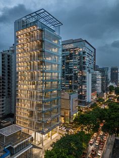 a very tall glass building sitting in the middle of a city at night with traffic passing by