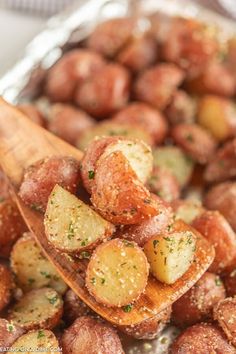 a wooden spoon full of cooked potatoes and parmesan cheese on a baking sheet