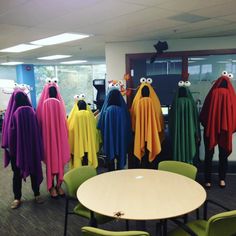 a group of people dressed up in colorful ponchles and scarves standing around a table