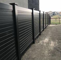 a row of black metal fences next to a brick wall and fenced in area