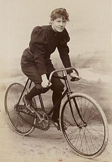 an old photo of a woman riding a bike