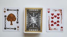 three playing cards with different designs on them, one in gold and the other in silver