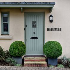 the front door of a house with two bushes and a sign on it that says stewart