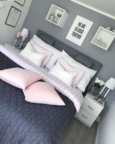 a bed with pink and white pillows in a bedroom next to pictures on the wall