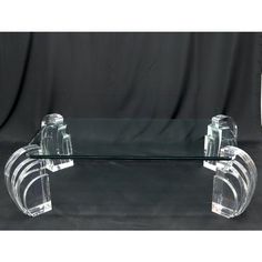 a clear glass coffee table with two legs and an acrylic design on top