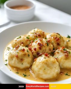 a white plate topped with dumplings covered in gravy next to a cup of coffee