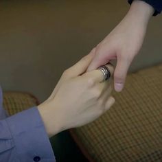 two people touching each other's fingers while sitting on a couch in the living room