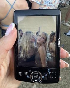 a person holding up a cell phone with the image of two women on it's screen