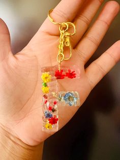 a hand holding a small plastic letter shaped keychain in it's palm